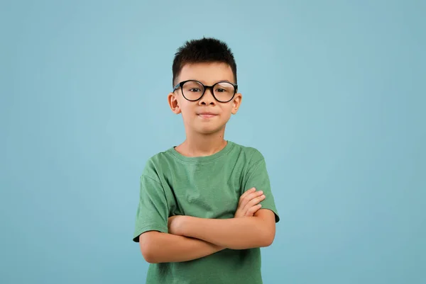 Gözlüklü gülümseyen küçük Asyalı çocuğun portresi katlanmış kollarıyla ayakta duruyor. — Stok fotoğraf