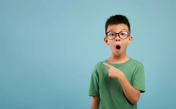 Úžasná nabídka. Vzrušený asijský chlapec s brýlemi ukazující ven v kopírovacím prostoru — Stock fotografie
