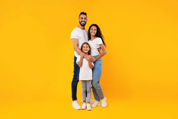 Prise de vue complète de la famille du Moyen-Orient étreignant debout sur fond jaune — Photo