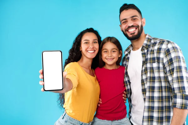 Família árabe mostrando tela do celular para câmera sobre fundo azul — Fotografia de Stock