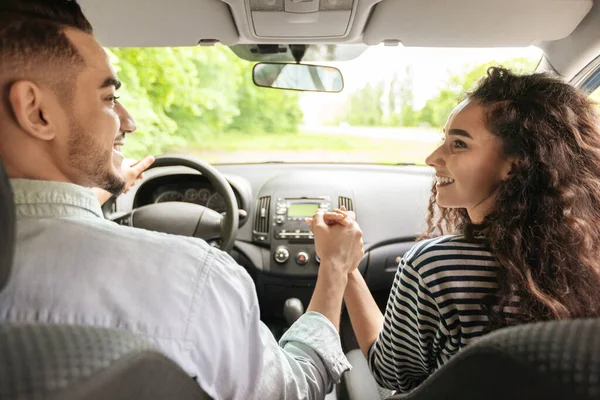 Liefdevol paar hand in hand zitten in auto, achteraanzicht — Stockfoto