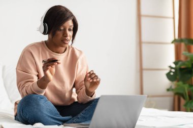 Siyah Kadın Freelancer, yatak odasında dizüstü bilgisayar kullanarak video görüşmesi yapıyor.
