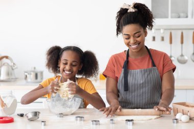Neşeli Afrikalı Amerikalı anne ve kızı hamur işi yapıyor.