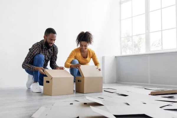 Sorrindo jovem família afro-americana se preparando para mover, empilhar caixas de papelão para as coisas na sala de estar interior — Fotografia de Stock