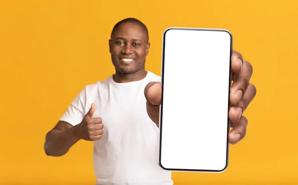 Mira esta aplicación. Hombre negro sonriente demostrando Smartphone con pantalla en blanco —  Fotos de Stock