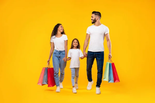Mellanösterns familj Shopping bär Shopper väskor promenader över gul bakgrund — Stockfoto