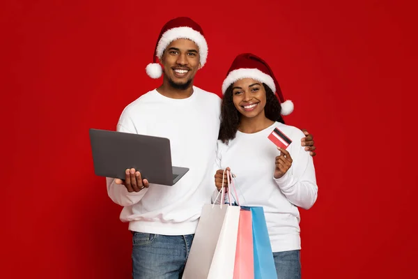 Glad svart par med kassar, laptop och kreditkort — Stockfoto