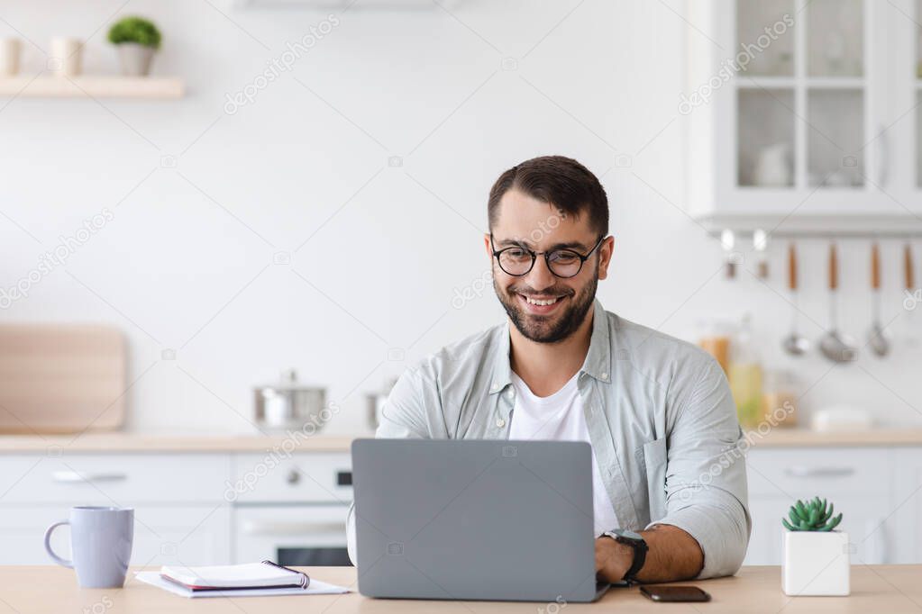 Smiling mature caucasian male manager or student with beard in glasses work at laptop