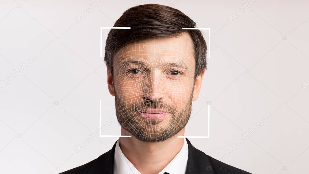 Friendly millennial businessman with stubble in suit scanning for facial recognition