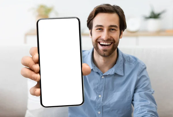 Opgewonden jonge man demonstreren smartphone met grote blanco witte scherm bij de camera — Stockfoto