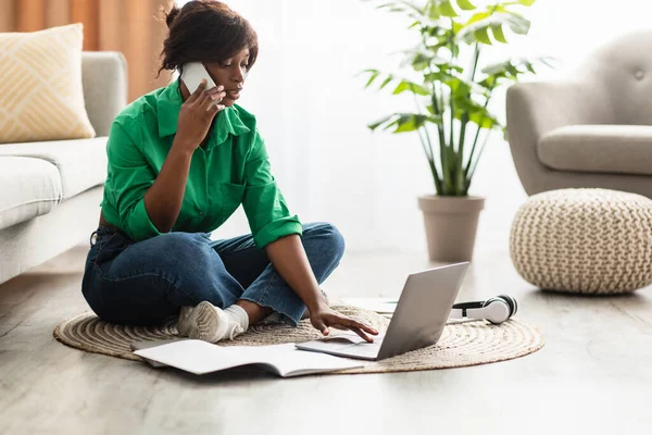 Afroamerykanka mówiąca przez telefon za pomocą laptopa w domu — Zdjęcie stockowe