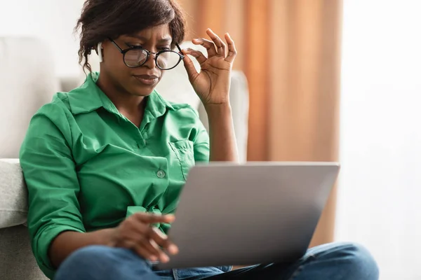 Černá žena se špatným zrakem pomocí notebooku nošení brýlí vnitřní — Stock fotografie