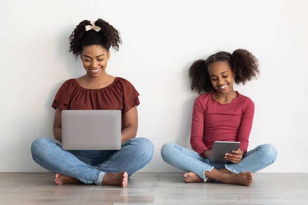 Mère noire positive avec ordinateur portable et fille avec tablette numérique — Photo