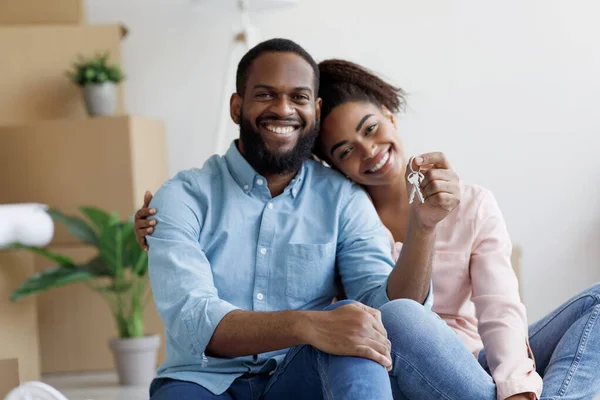 Alegres jovens afro-americanos mostrar chave e desfrutar de compra de imóveis no quarto com caixas de papelão — Fotografia de Stock