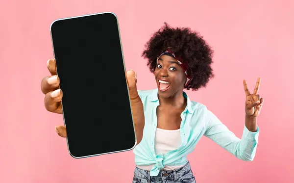 Gran aplicación. Mujer negra sosteniendo Smartphone con pantalla en blanco y gestos de paz — Foto de Stock