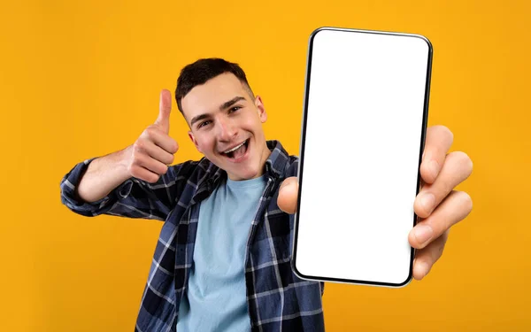 Anúncio de aplicação móvel. Jovem animado mostrando smartphone com tela branca em branco — Fotografia de Stock