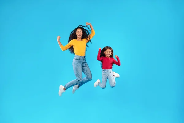 Madre e figlia arabe che saltano in posa a mezz'aria, sfondo blu — Foto Stock