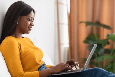 Kulaklıklı Afrikalı Amerikalı Kadın Evde, Yan Görünüşte Laptop Kullanıyor