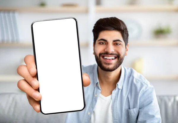 Alegre hombre árabe mostrando Smartphone con gran pantalla blanca en blanco en la cámara — Foto de Stock