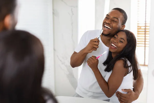 Vrolijk Afrikaans Amerikaans paar hebben plezier terwijl borstelen tanden in badkamer samen — Stockfoto