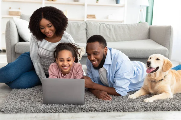 Negro familia usando pc relajarse con el perro en casa — Foto de Stock