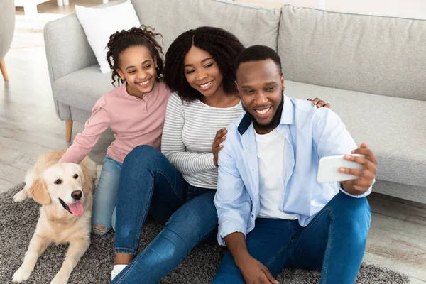 Joven familia negra tomando selfie con mascota en casa — Foto de Stock