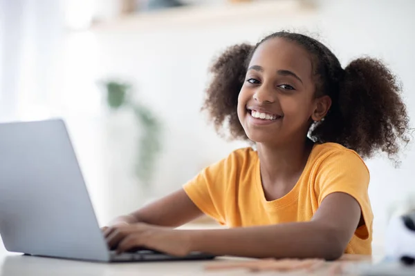 Veselý černošky dívka studuje on-line, pomocí notebooku, psaní na klávesnici — Stock fotografie