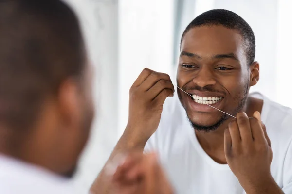 Higiene oral. Joven afroamericano chico usando hilo dental en baño — Foto de Stock