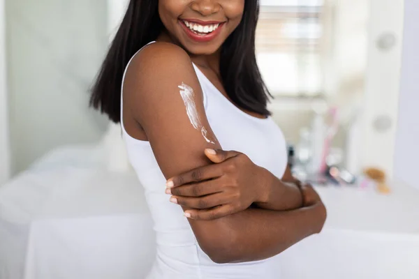 Close-up van jonge Afro-Amerikaanse vrouw toepassen hydraterende body lotion op de schouder — Stockfoto