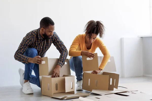 Ocupado milenar Africano americano marido e mulher se preparando para mover, empilhar caixas de papelão para as coisas — Fotografia de Stock