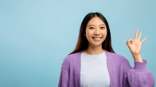 Femme asiatique positive montrant Ok geste et sourire à la caméra, signe gestuel d'approbation sur fond bleu, panorama — Photo