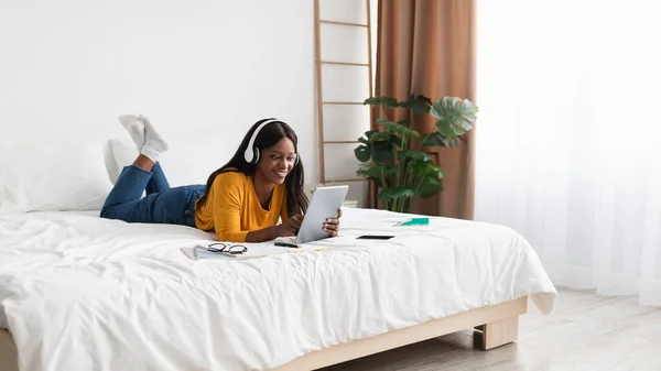 Schwarze Frau mit Tablet trägt Kopfhörer im Schlafzimmer, Panorama — Stockfoto
