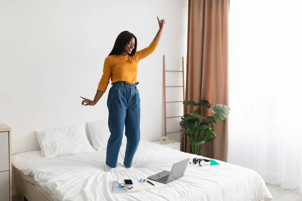 Gelukkig Afrikaans vrouw luisteren muziek op laptop dansen in slaapkamer — Stockfoto
