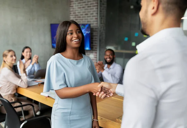Männlicher Chef beim Händeschütteln und Begrüßung afroamerikanischer Mitarbeiterinnen im Büro — Stockfoto