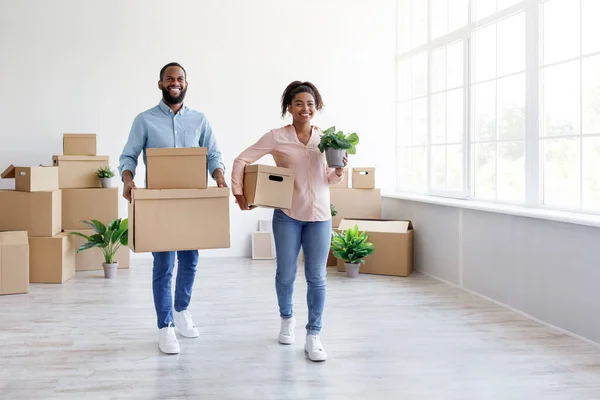 Satisfecho feliz millennial afroamericano masculino y femenino llevar cajas de cartón con pertenencias en habitación vacía —  Fotos de Stock