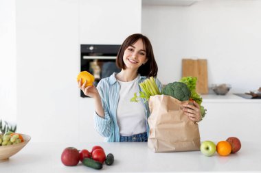 Sağlıklı beslenme ve yaşam tarzı. Taze organik sebzeler, sebzeler ve meyvelerle dolu paketleri açan mutlu genç bayan.