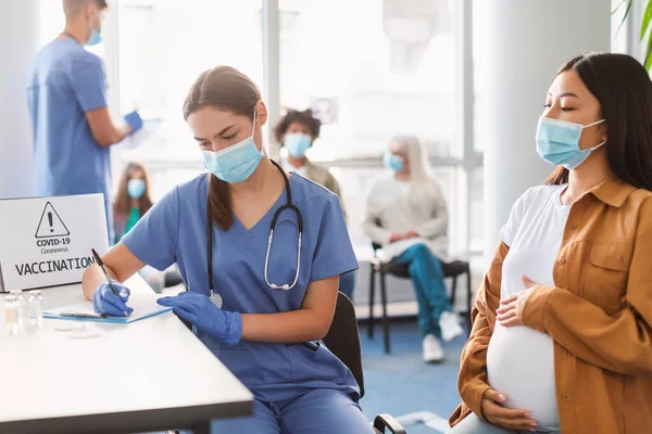 Těhotná dáma v masce na schůzku v ordinaci lékařů — Stock fotografie