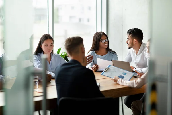 Alegre equipo empresarial multiétnico joven que se reúne durante la reunión corporativa en la oficina — Foto de Stock