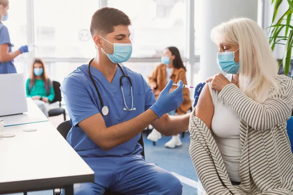 Señora mayor que recibe la inyección de la vacuna en el brazo en el centro médico —  Fotos de Stock