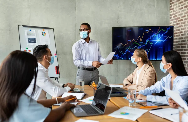 Reunión de negocios. Negro Ceo Hombre en la cara de la máscara de hacer la presentación a los compañeros de trabajo en la oficina — Foto de Stock