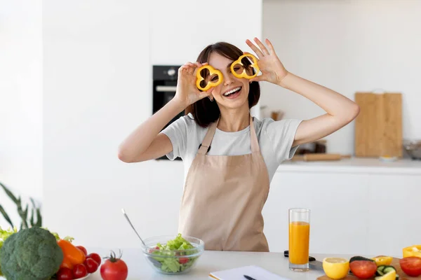 Köket roligt. Rolig ung kvinna gör glas paprika, matlagning färska friska vegan sallad i köket — Stockfoto