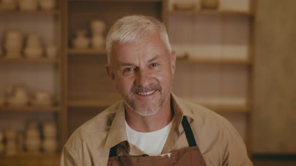 Retrato de hombre Potter profesional sonriendo usando delantal en el estudio — Vídeo de stock