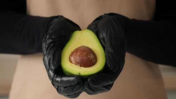 Cuoco irriconoscibile che tiene avocado mezzo indossando guanti all'interno, primo piano — Video Stock