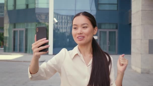 Señora coreana haciendo videollamada en el teléfono en el área urbana — Vídeos de Stock