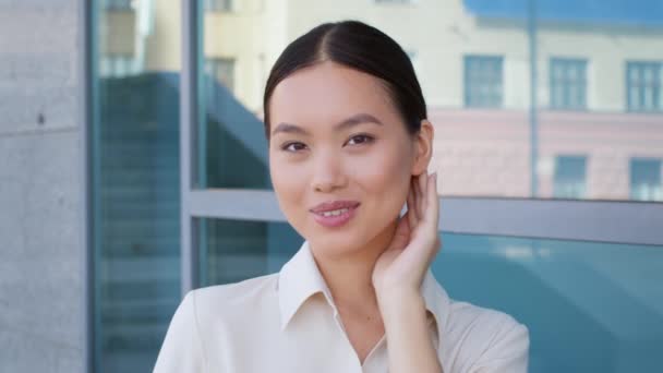 Aziatisch zakenvrouw glimlachen naar camera poseren in de buurt van modern gebouw buiten — Stockvideo