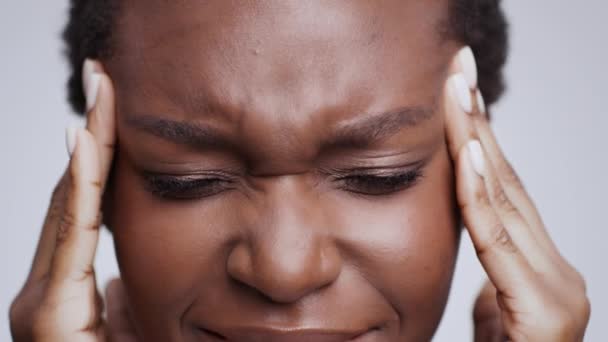 Pressão arterial e dor de cabeça. Close up retrato de jovem afro-americana deprimida massageando seus templos doloridos — Vídeo de Stock