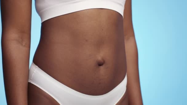 Piękno kobiecego ciała. Nierozpoznawalna Afroamerykanka w bieliźnie pozująca na niebieskie tło, wolna przestrzeń — Wideo stockowe