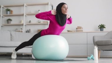 Sırt ve çekirdek güçlendirme egzersizi. Genç müslüman kadın tesettüre girmiş evde spor yaparken karın kası egzersizi yapıyor.