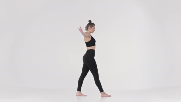 Jóga edzés. Fiatal vékony rugalmas hölgy fekete sportruházat lép előre, és hajlik le a lábát, oldalnézetből — Stock videók