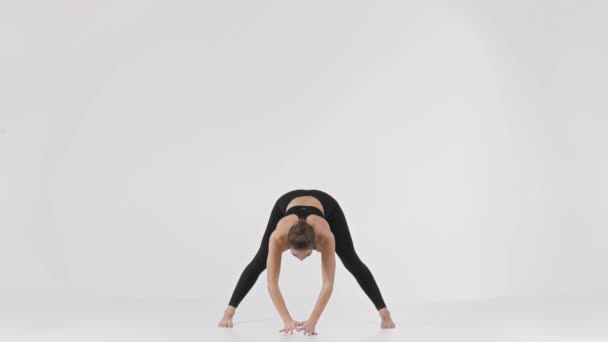 Jovem mulher desportiva treinador fitness demonstrando triângulo ioga asana, inclinando para a frente e levantando as mãos — Vídeo de Stock